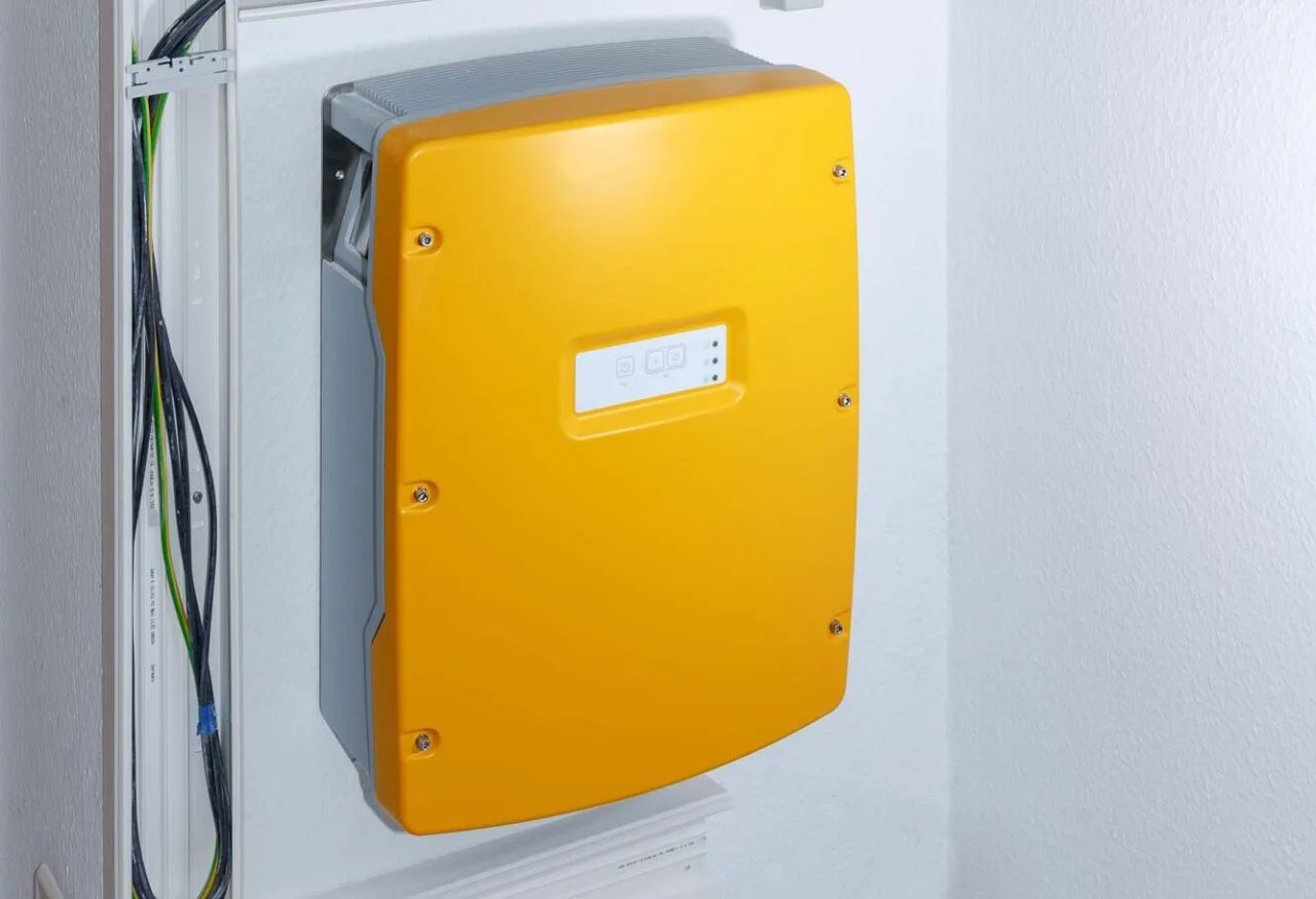 Gelber Wechselrichter einer Photovoltaikanlage an der Wand – Einspeisevergütung Köln.