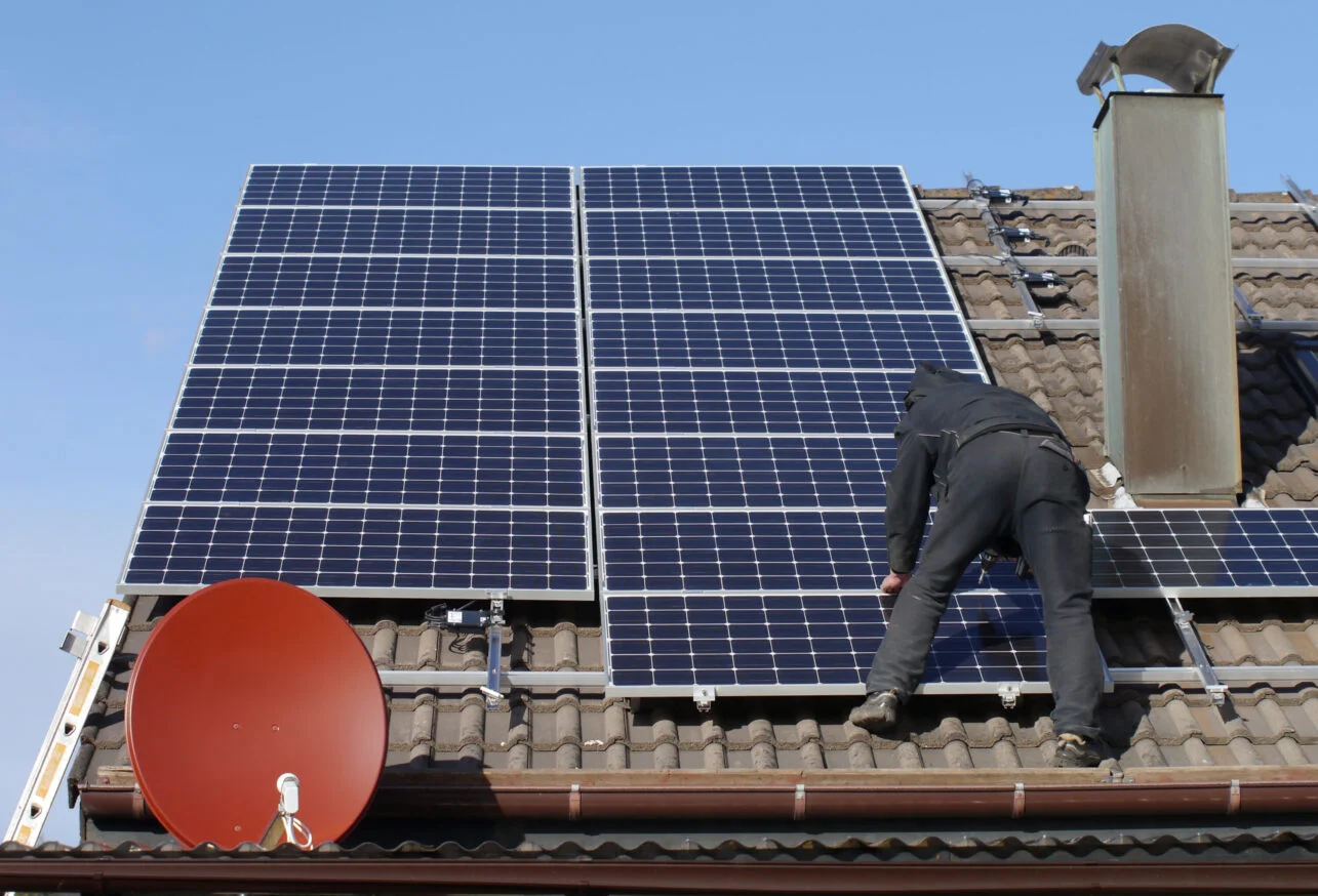 Monteur rüstet bestehende Photovoltaikanlage auf Hausdach nach – Nachrüstung PV Köln.